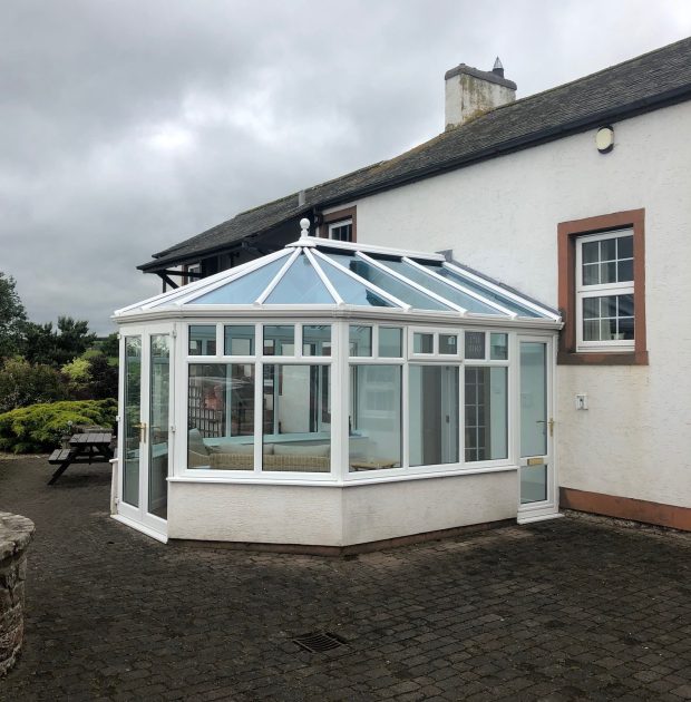 Conservatory extension on the rear of a home, with white frames.