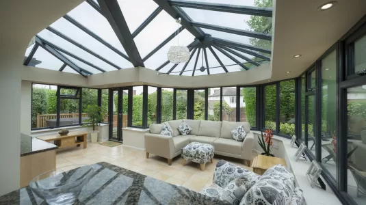 Interior of an orangery conservatory extension, featuring kitchen counter top and modern, stylish furniture.