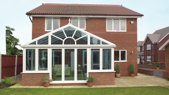 A glass conservatory extension on the rear of a home, with white frames.