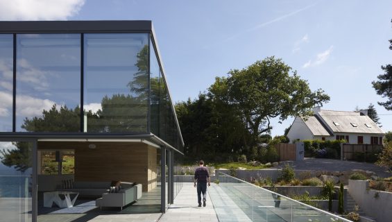 The exterior of a modern home with large, fixed windows covering the second level, with a mezzanine on the ground floor.