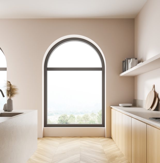 Large arched window with dark grey frames, in a modern and minimalist kitchen